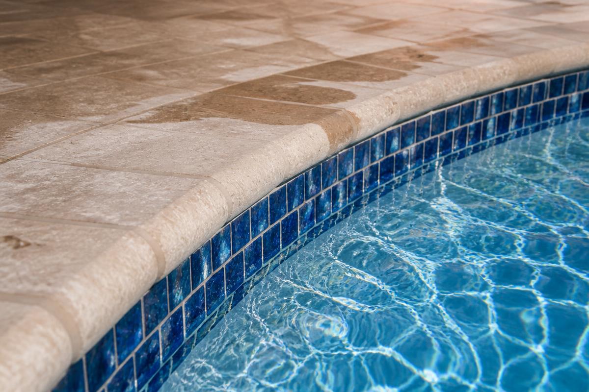 Blue pool tile and stone coping above sparkling water